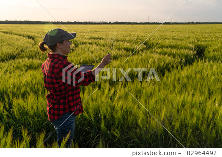 Farmer with digital tablet on a rye field. Smart farming and digital transformation in agriculture.. 102964492