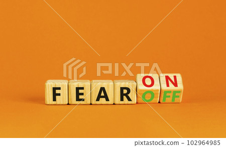 Fear on or off symbol. Businessman turns wooden cubes and changes word Fear off to Fear on. Beautiful orange table orange background. Business and fear on or off concept. Copy space. Fear on or off symbol. Businessman turns wooden cubes and changes word Fear off to Fear on. Beautiful orange table orange background. Business and fear on or off concept. Copy space. 102964985