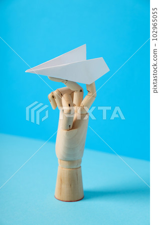 Wooden hand with paper plane on blue background Wooden hand with paper plane on blue background 102965055