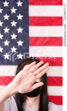 Unrecognized woman stretch out her palm to camera says stop abortion American flag on background. Selective focus. Anti domestic violence, racism racial discrimination. Women rights, social problems. 102965117