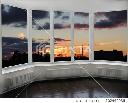 Panoramic window with view of red sunset above city buildings. Raising sun Panoramic window with view of red sunset above city buildings. Raising sun 102966086