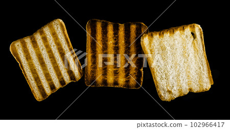 Three slices of toasted bread on the grill on a black background. Toast bread. Three slices of toasted bread on the grill on a black background. Toast bread. 102966417