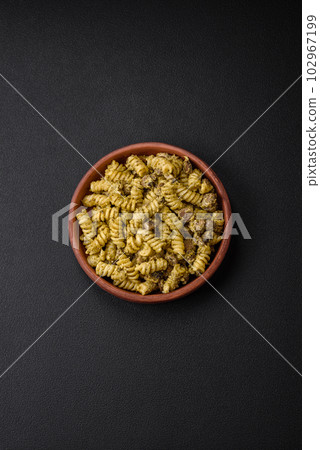 Delicious fusilli pasta with green pesto sauce, with salt and spices 102967199