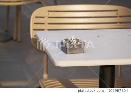 Close up burning cigarette in ashtray on table Close up burning cigarette in ashtray on table 102967894
