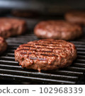 Delicious hamburger patty on grill 102968339