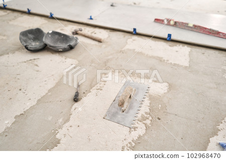 Tiler tool. Repair of the dining room in the house, place for kitchen, floor covering change. Empty interior for design, gray concrete wall. 102968470