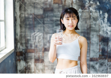 A woman holding a glass of water 102968697
