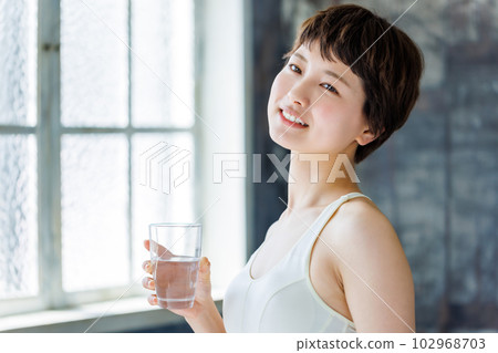 A woman holding a glass of water 102968703