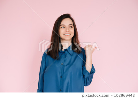 Radiant Portrait of Beautiful Woman with Joyful Smile, Pointing Finger and Looking at Empty Space Radiant Portrait of Beautiful Woman with Joyful Smile, Pointing Finger and Looking at Empty Space 102969448
