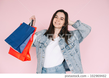 Joyful Shopper: Young Woman in Denim Shirt Celebrating, Arm Raised in Excitement, Against Pink 102969482