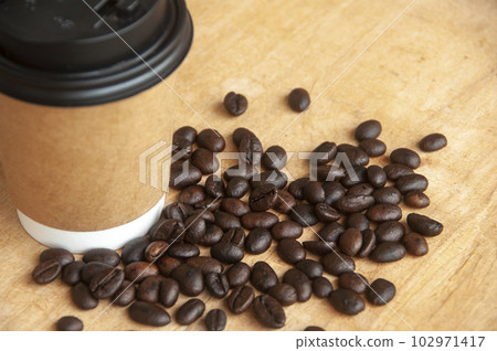 Takeaway coffee cup surrounded with coffee beans with customizable space for text or ideas. Copy space and coffee concept Takeaway coffee cup surrounded with coffee beans with customizable space for text or ideas. Copy space and coffee concept 102971417
