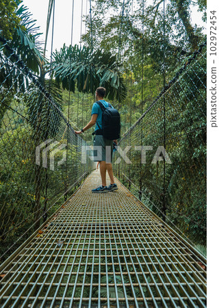 Arenal Hanging Bridges, young man hiking in green tropical jungle, Costa Rica, Central America. 102972454
