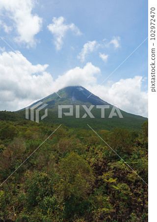 Amazing view of beautiful nature of Costa Rica with cloudy volcano Arenal background. Panorama of volcano Arenal reflected on wonderful picturesque lake, La Fortuna, Costa Rica. Central America. Amazing view of beautiful nature of Costa Rica with cloudy volcano Arenal background. Panorama of volcano Arenal reflected on wonderful picturesque lake, La Fortuna, Costa Rica. Central America. 102972470