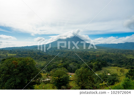 Amazing view of beautiful nature of Costa Rica with cloudy volcano Arenal background. Panorama of volcano Arenal reflected on wonderful picturesque lake, La Fortuna, Costa Rica. Central America. Amazing view of beautiful nature of Costa Rica with cloudy volcano Arenal background. Panorama of volcano Arenal reflected on wonderful picturesque lake, La Fortuna, Costa Rica. Central America. 102972604