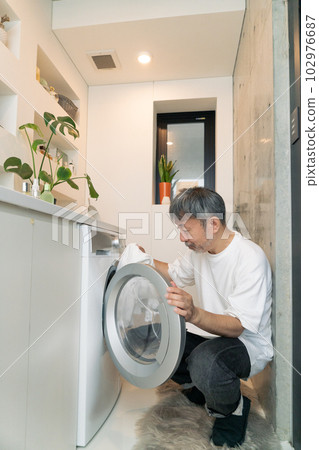Middle-aged man doing laundry Vertical position 102976687