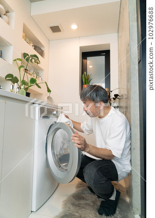 Middle-aged man doing laundry Vertical position 102976688