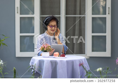 Senior woman is listen music and pose share good news at social media via  computer tablet. 102977258