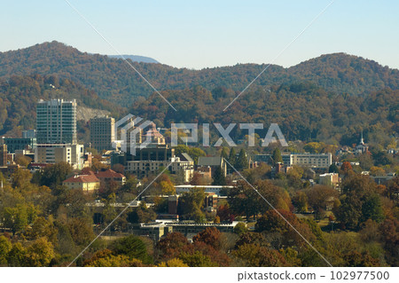 Aerial view of Asheville city in North Carolina with high buildings and mountain hills in distance 102977500