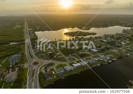 Aerial view of american suburban area with rural road roundabout intersection with moving cars traffic. Circular transportation crossroads in Florida 102977506