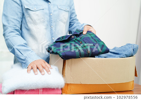 Clothes donations in cardboard box for volunteer. 102978556