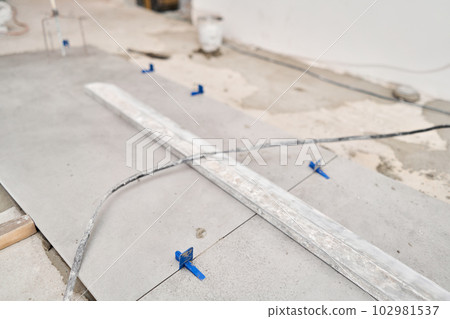 Tiler work. Repair of the dining room in the house, place for kitchen, floor covering change. Empty interior for design, gray concrete wall. 102981537