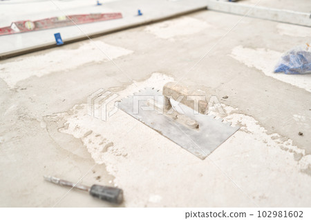 Tiler tool. Repair of the dining room in the house, place for kitchen, floor covering change. Empty interior for design, gray concrete wall. 102981602