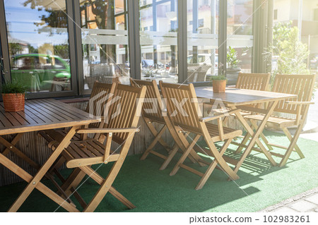 Outdoor cafe with wooden chairs in soft sunlight Outdoor cafe with wooden chairs in soft sunlight 102983261