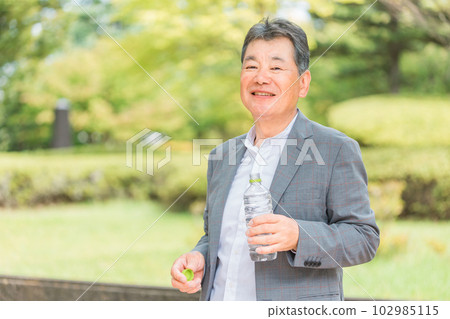 Asian elderly men drinking water and hydrating while walking Asian elderly men drinking water and hydrating while walking 102985115