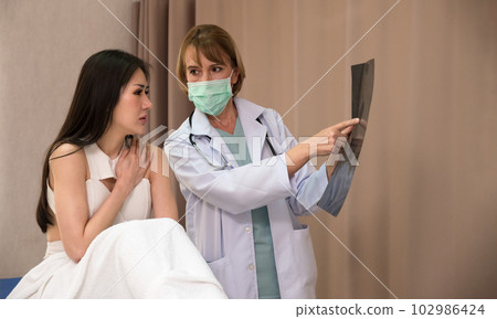 Female medical doctor give consultation to asian patient with x-ray film in hospital 102986424