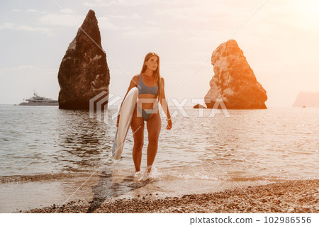 Woman sea sup. Close up portrait of happy young caucasian woman with long hair looking at camera and smiling. Cute woman portrait in bikini posing on sup board in the sea 102986556