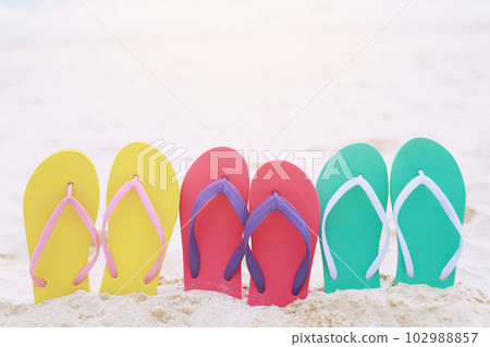 sea on the beach Footprint  people on the sand and slipper of feet in sandals shoes on beach sands background. travel holidays concept. 102988857