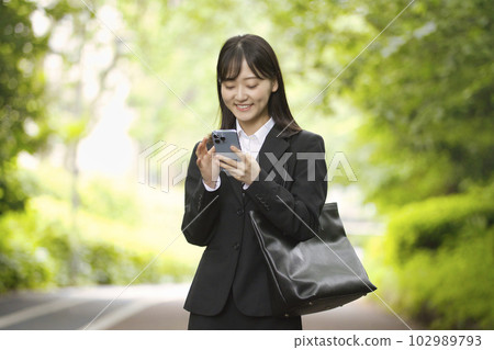 穿著招聘服的年輕女子看著智能手機 穿著招聘服的年輕女子看著智能手機 102989793