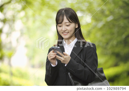 穿著招聘服的年輕女子看著智能手機 穿著招聘服的年輕女子看著智能手機 102989794