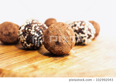 Energy balls in white bowl. Healthy raw dessert, vegetarian truffles, sugar free candies made of dates, hazelnuts, cocoa powder. Energy balls in white bowl. Healthy raw dessert, vegetarian truffles, sugar free candies made of dates, hazelnuts, cocoa powder. 102992043