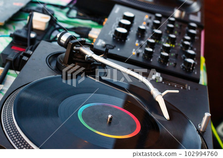Vinyl record on a deejay's turntable with mixing desk equipment sound system Vinyl record on a deejay's turntable with mixing desk equipment sound system 102994760