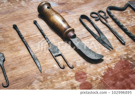A selection of medieval surgical instruments on a blood-splattered wooden table A selection of medieval surgical instruments on a blood-splattered wooden table 102996895
