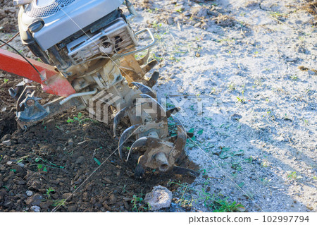 There is farmer plows ground in garden with tiller block using motor cultivator There is farmer plows ground in garden with tiller block using motor cultivator 102997794