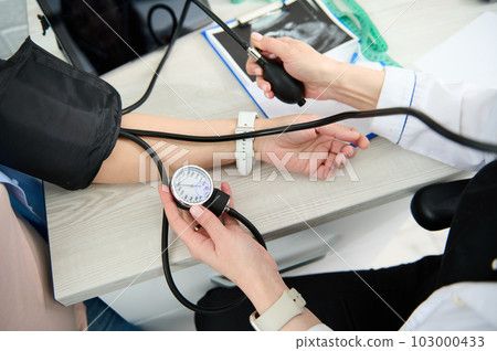 Close-up top view of a gynecological nurse using tonometer, checking blood pressure of a pregnant woman, to prevent and early diagnostic of the the pregnancy induced hypertension, pre-eclampsia 103000433