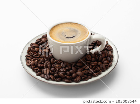 Espresso coffee in small cup and fresh raw beans on saucer on white Espresso coffee in small cup and fresh raw beans on saucer on white 103008544