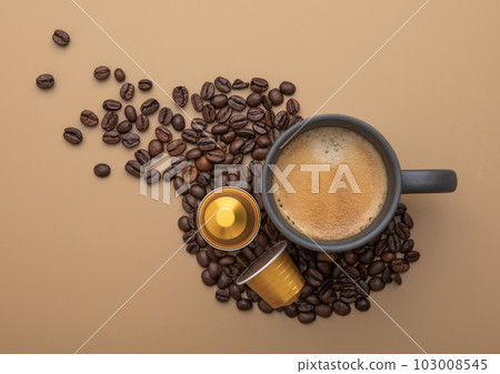 Coffee cup with fresh raw beans and coffee capsules on beige background. Coffee cup with fresh raw beans and coffee capsules on beige background. 103008545