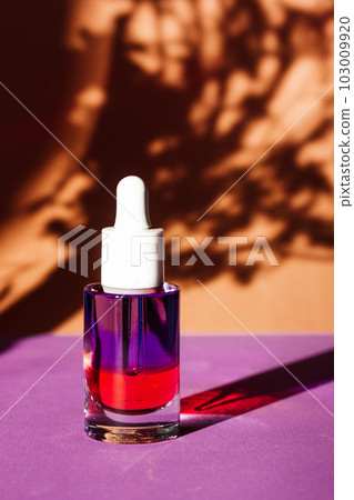 Glass jar of facial serum on brown natural background with plant contrast shadow pattern. Cosmetics and body care. Cuticle oil. Cosmetic bottle with pipette. Minimalistic stylish daily care routine. Glass jar of facial serum on brown natural background with plant contrast shadow pattern. Cosmetics and body care. Cuticle oil. Cosmetic bottle with pipette. Minimalistic stylish daily care routine. 103009920