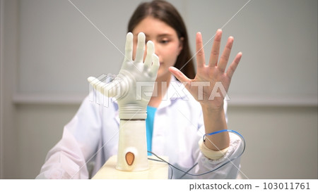 Technician testing robotic bionic arm at prosthetic manufacturing Technician testing robotic bionic arm at prosthetic manufacturing 103011761