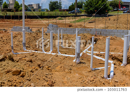 It is job of plumber to lay sewage and water pipes utility lines in ground under foundation new home 103011763