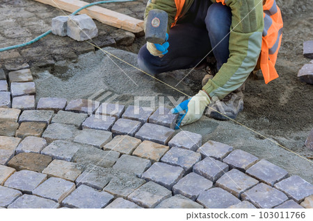 Worker were carefully laying granite stones and using industrial cobblestones to create durable and long lasting pavement. 103011766