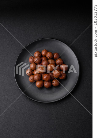 Delicious roasted macadamia nuts in shell on a dark textured background 103012775