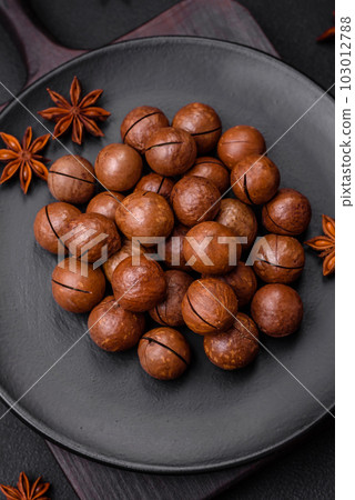 Delicious roasted macadamia nuts in shell on a dark textured background 103012788
