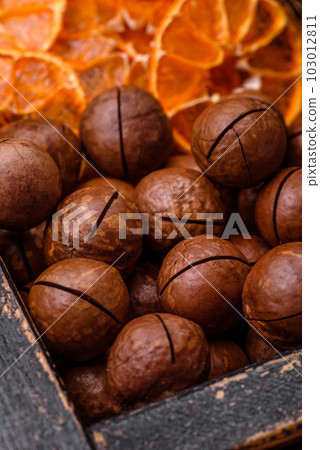Delicious roasted macadamia nuts in shell on a dark textured background 103012811