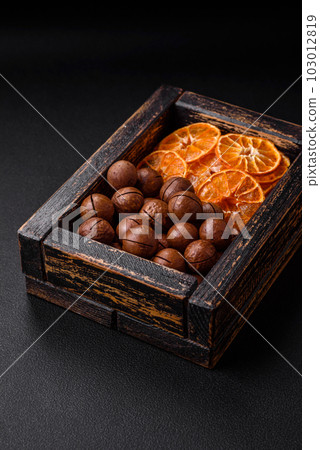 Delicious roasted macadamia nuts in shell on a dark textured background 103012819