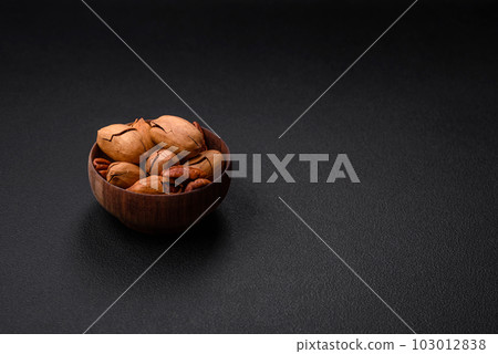 Pecan nuts in shell and peeled in a wooden round bowl 103012838