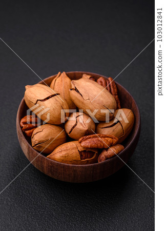 Pecan nuts in shell and peeled in a wooden round bowl 103012841